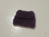 Purple beaded bag on a white surface with a tiled floor in the background
