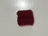Red beaded bag on a white surface with a shadow cast by a person.