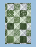 Patchwork quilt with a geometric pattern on a light greens and white  background