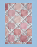 Patchwork quilt with a geometric pattern on a light pink background