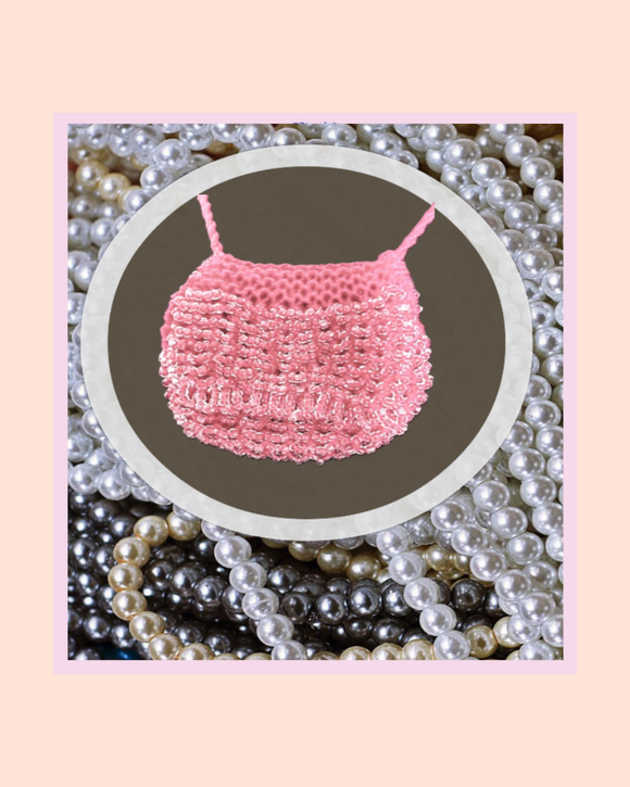 Pink beaded necklace on a dark background with pearls around
