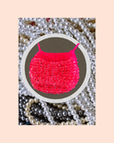 Pink bead knitted bag on a bed of pearls with a beige background
