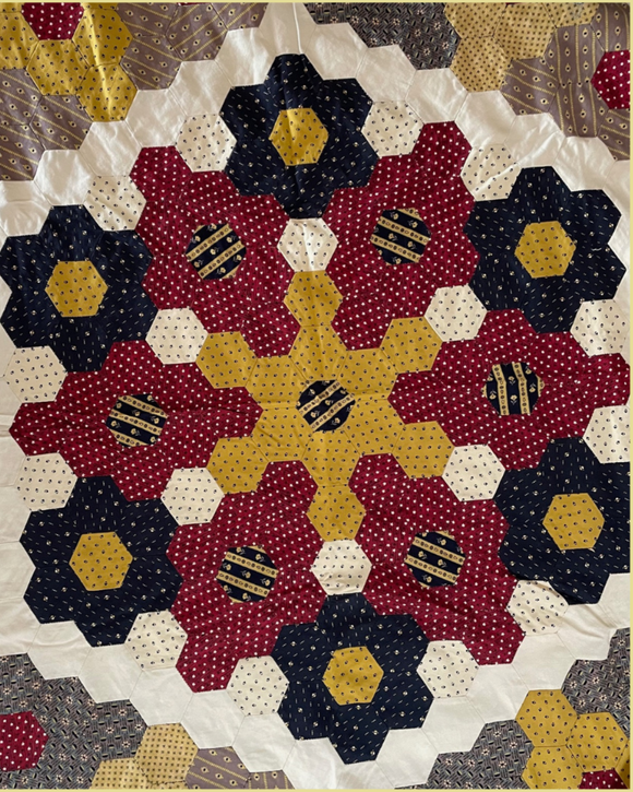 Hexagon Quilt pattern with floral designs in red, yellow, and blue on a white background