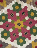 Hexagon Quilt pattern with floral designs in red, yellow, and green on a white background