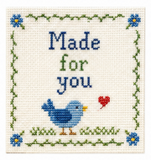 Cross-stitched design with a blue bird, red heart, and text 'Made for you' on a white background.