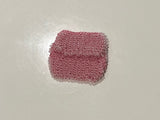 Pink beaded bag on a white surface with a tiled floor background