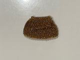Golden brown beaded purse ace with a shadow cast by an object.